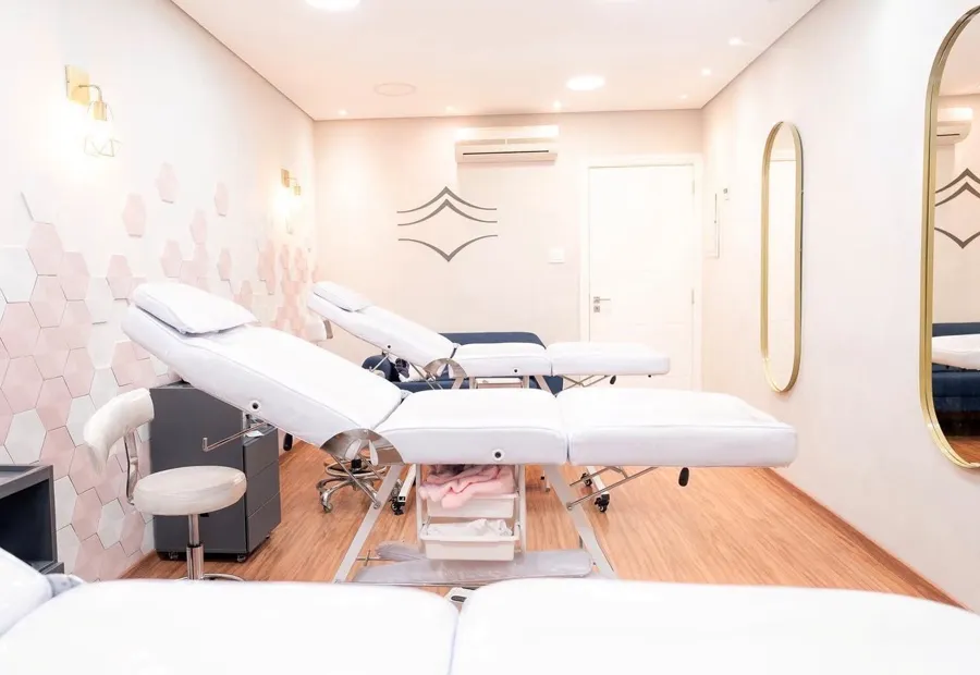 Sala de estética com macas e paredes em tons rosados